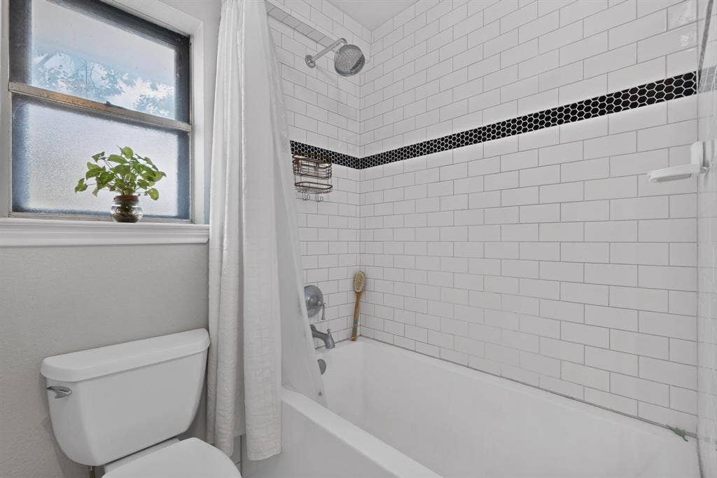 2003 J J Pearce Drive, Richardson, TX 75081 Bathroom featuring a white subway tile shower surround with a black hexagonal accent band, a tub/shower combination, and a white toilet