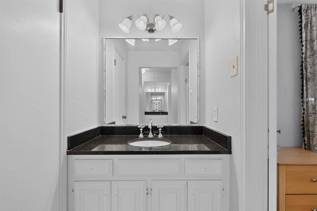 2003 J J Pearce Drive, Richardson, TX 75081 Bathroom vanity matching on the opposite of the bathroom with a dark countertop and undermount sink