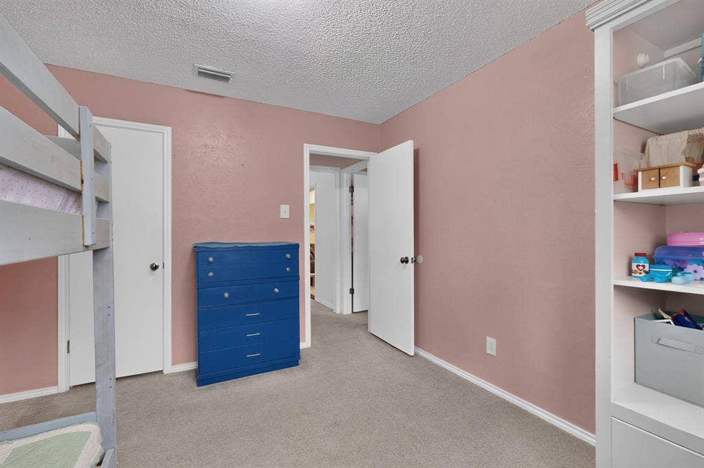 2003 J J Pearce Drive, Richardson, TX 75081 Interior room with textured ceiling, light pink walls, light gray carpeting, white trim, and a built-in white shelving unit