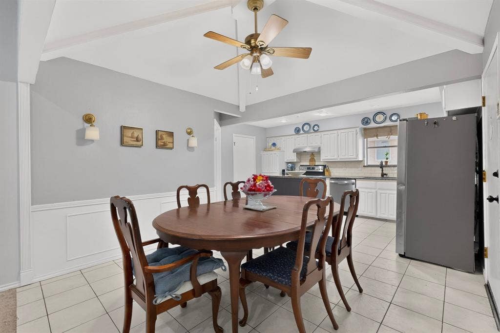 2003 J J Pearce Drive, Richardson, TX 75081 Dining area featuring light gray walls with white wainscoting, white tile flooring, and a ceiling fan with light fixture