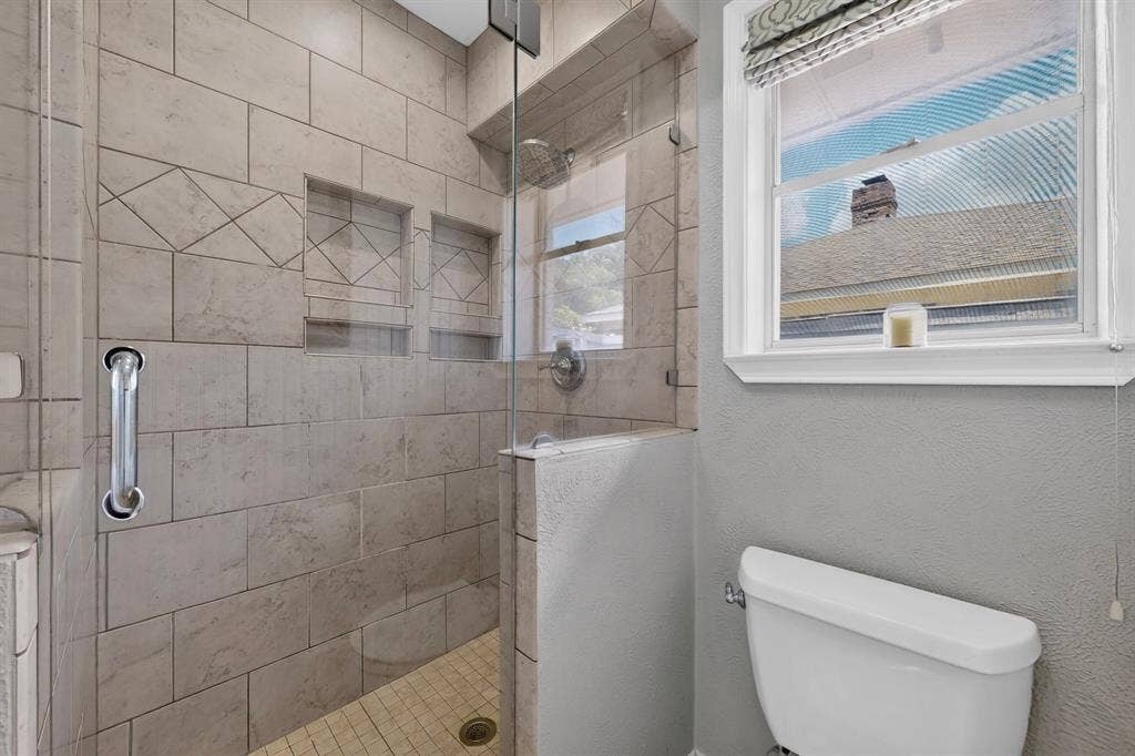 2003 J J Pearce Drive, Richardson, TX 75081 Walk-in shower featuring light-toned tile, glass enclosure, dual built-in shower niches, and a rainfall showerhead