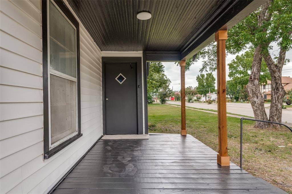 Covered front porch featuring wood-finish support columns and a dark painted floor
