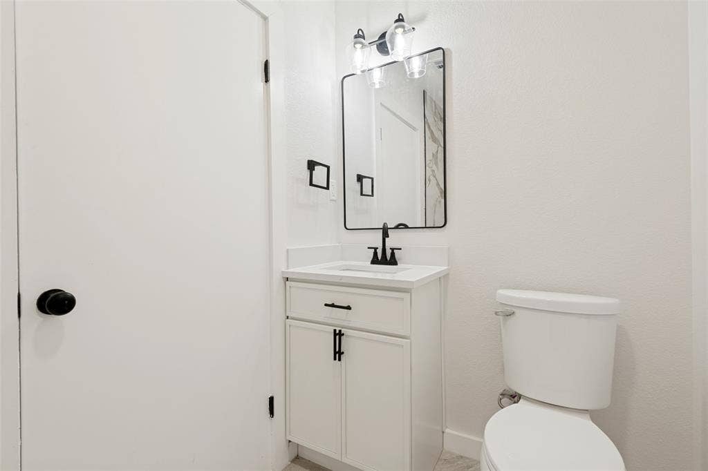 Bathroom vanity featuring a white countertop, under-mount sink, and matte black faucet
