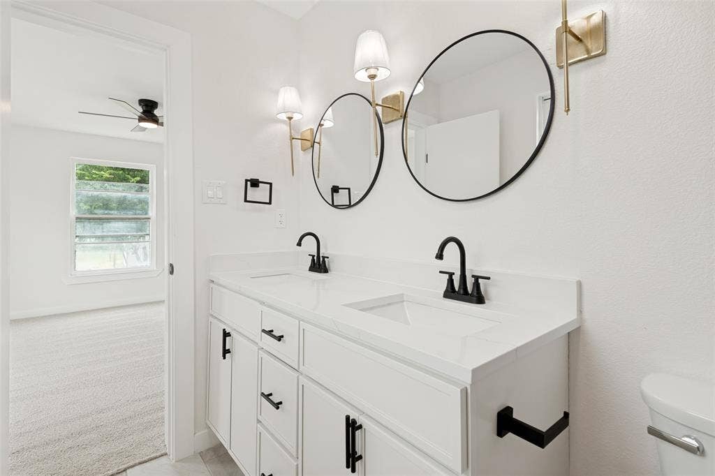Dual vanity featuring white cabinetry, integrated sinks, black fixtures, and a white countertop