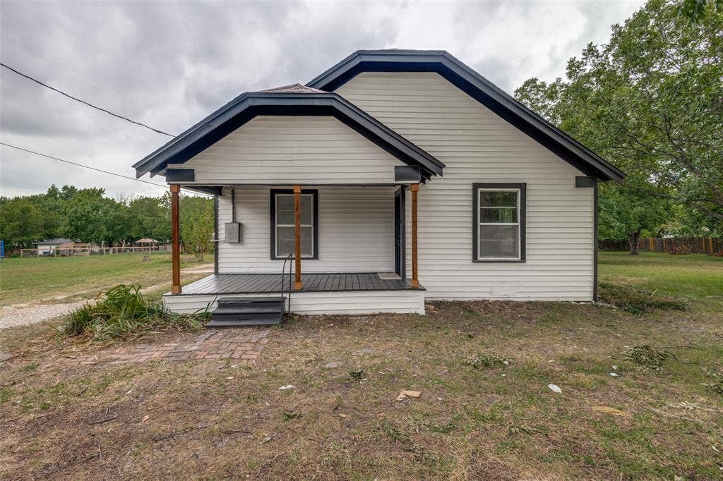 White siding exterior featuring a covered porch with dark flooring and wooden support beams