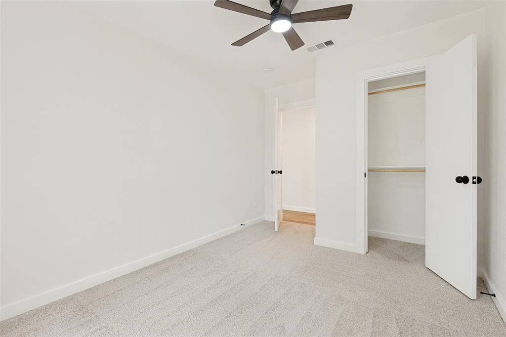 Carpeted room featuring a ceiling fan with integrated lighting, white walls, and a closet with bi-fold doors