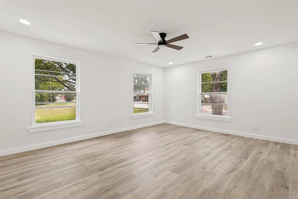 Spacious room featuring light wood-finish flooring, recessed lighting, and a contemporary ceiling fan