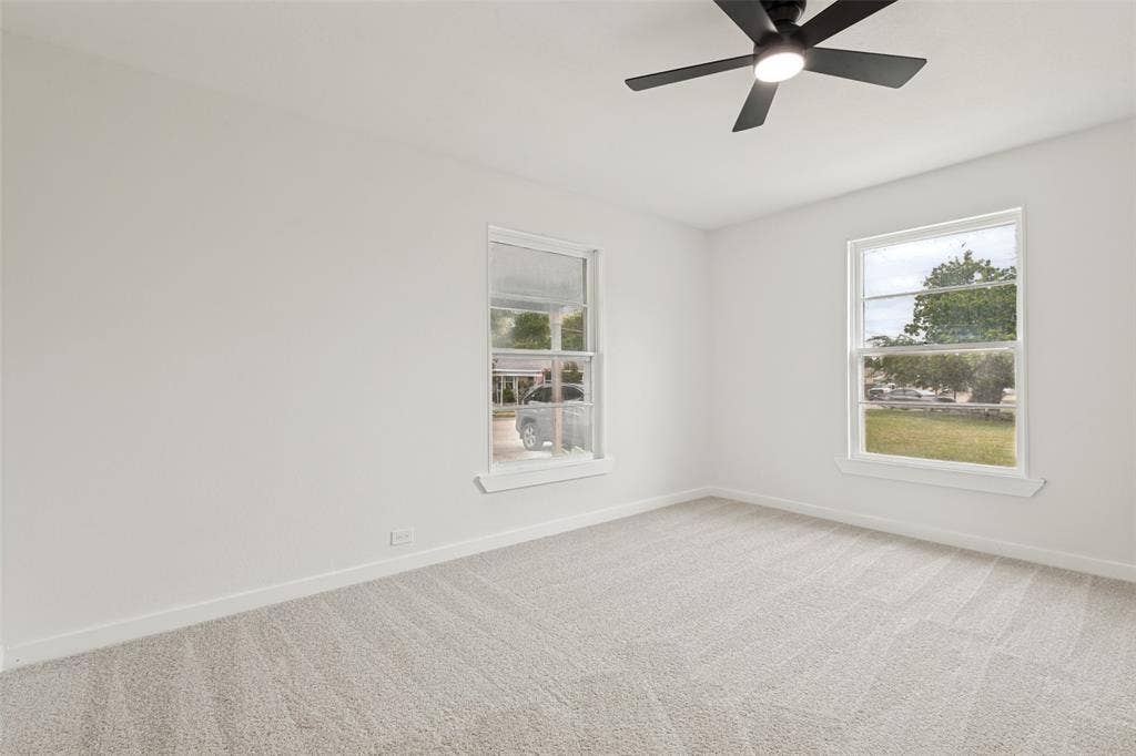 Carpeted room with two large windows and a ceiling fan with integrated lighting