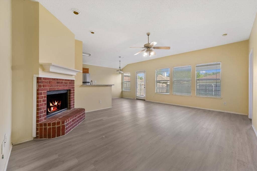 2312 Corral Drive, Fort Worth, TX 76133 Spacious living area featuring wood-finish flooring, a brick fireplace with a white mantel, recessed lighting, and multiple windows