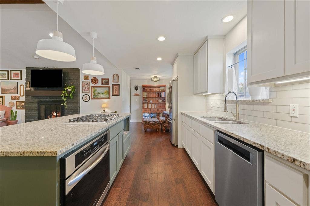 1112 Woodmount Court, Denton, TX 76209 Open-concept kitchen with oversized island, gas cooktop, granite countertops, stainless steel appliances, and seamless flow into the living and dining areas.