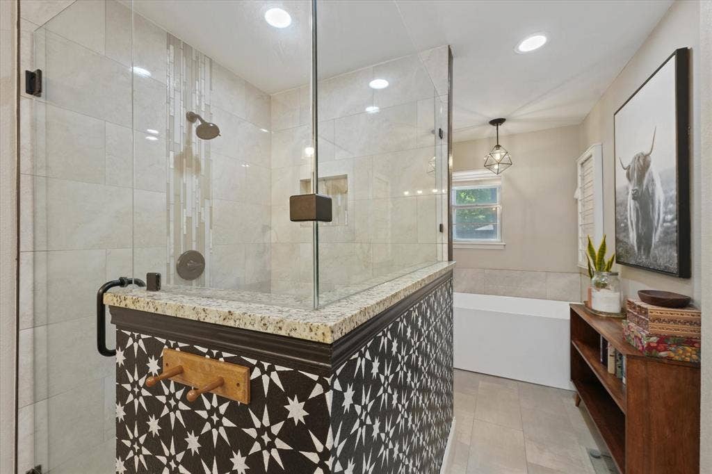 1112 Woodmount Court, Denton, TX 76209 Beautifully renovated primary bathroom with oversized walk-in shower, freestanding soaking tub, dual granite vanities, custom tile, and designer finishes.