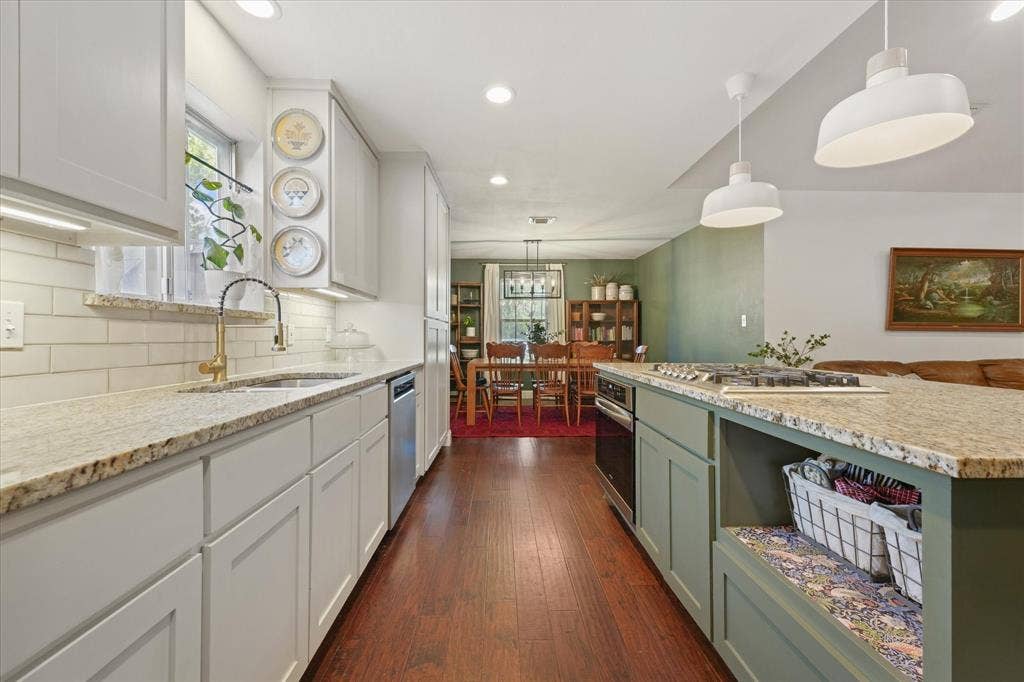1112 Woodmount Court, Denton, TX 76209 Renovated kitchen featuring granite countertops, shaker-style cabinetry, subway tile backsplash, under-cabinet lighting, stainless steel appliances, and a large center island.