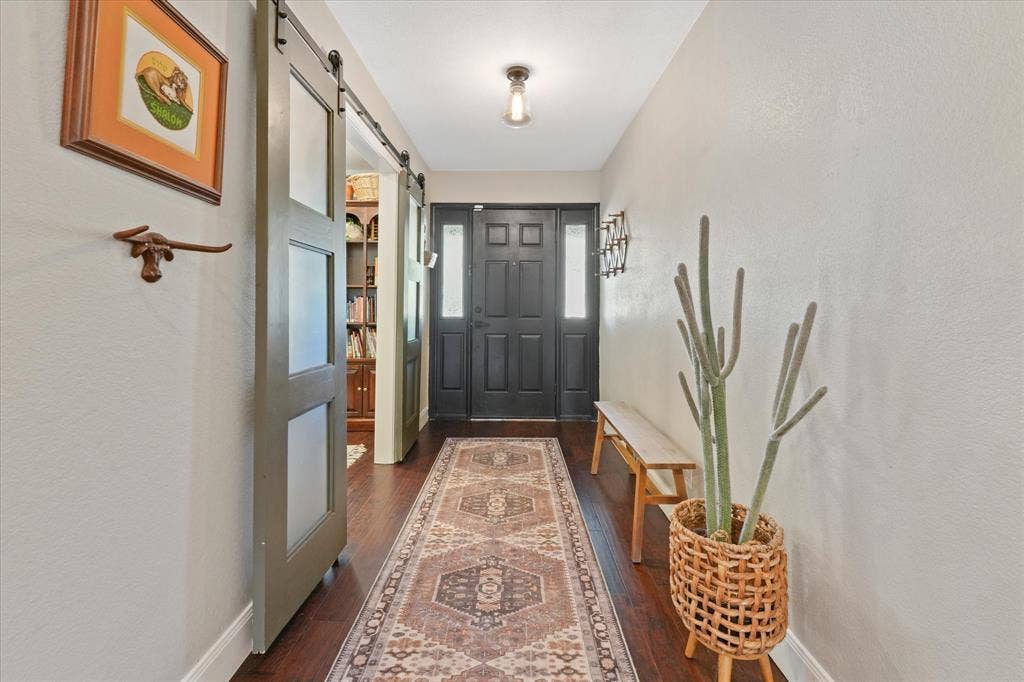 1112 Woodmount Court, Denton, TX 76209 Long welcoming foyer with hardwood floors, updated front door, and sliding barn doors opening to a private flex room or home office.