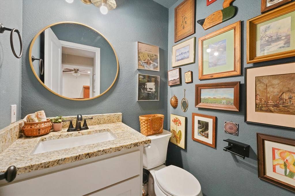 1112 Woodmount Court, Denton, TX 76209 Updated guest half bath with granite countertop, modern vanity, updated fixtures, and stylish accent wall.