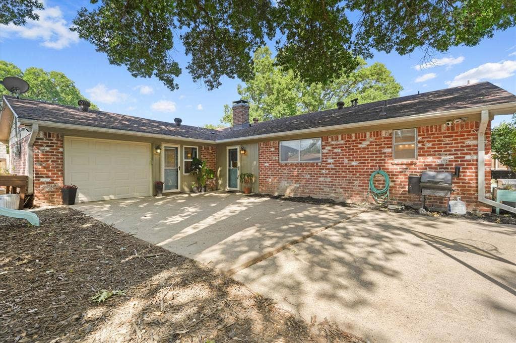 1112 Woodmount Court, Denton, TX 76209 Large concrete patio overlooking the backyard with direct access to the home, ideal for outdoor dining, grilling, relaxing, or hosting gatherings beneath mature shade trees.