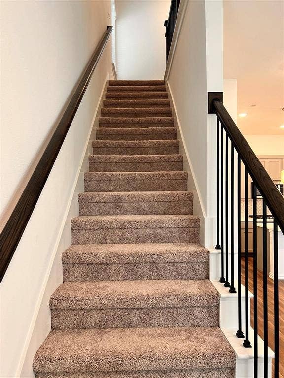 1054 Old Rosebud Drive, Allen, TX 75013 Carpeted staircase featuring a dark wood-finish handrail and black metal balusters