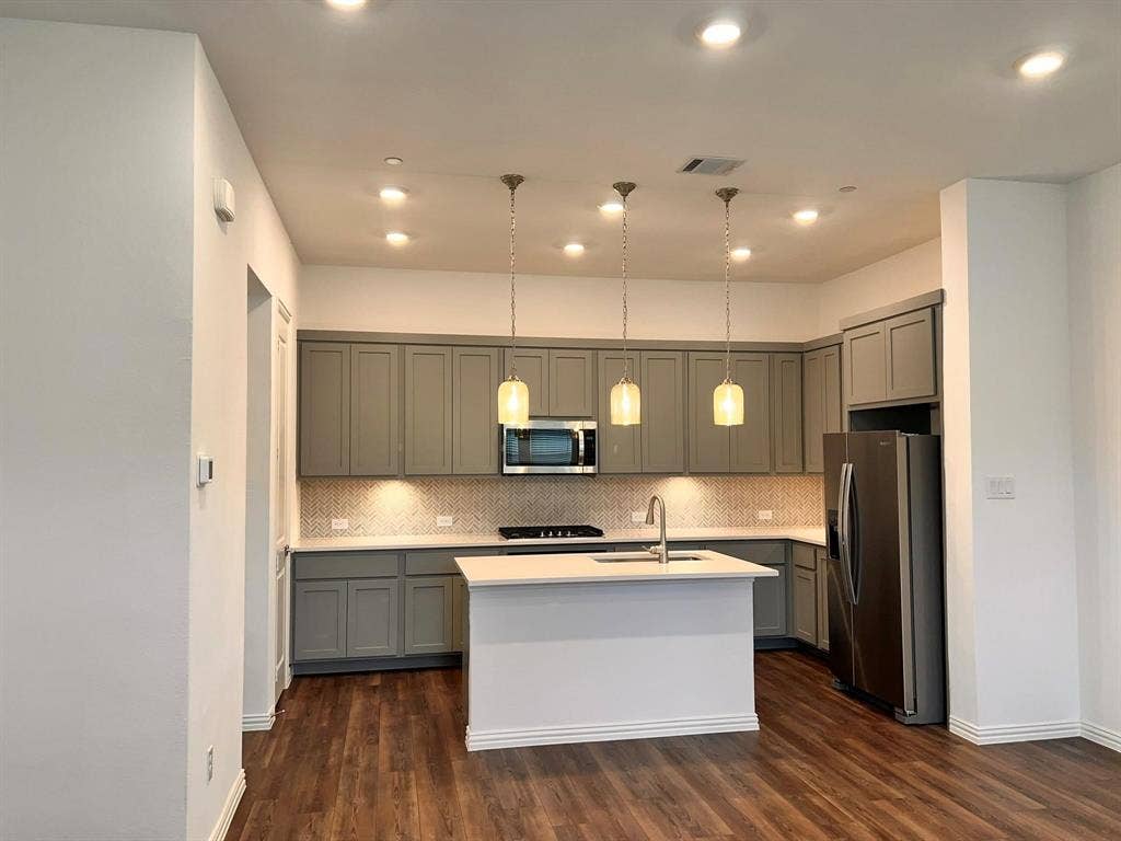 1054 Old Rosebud Drive, Allen, TX 75013 Contemporary kitchen featuring gray shaker-style cabinetry, a white island with an undermount sink, and stainless steel appliances