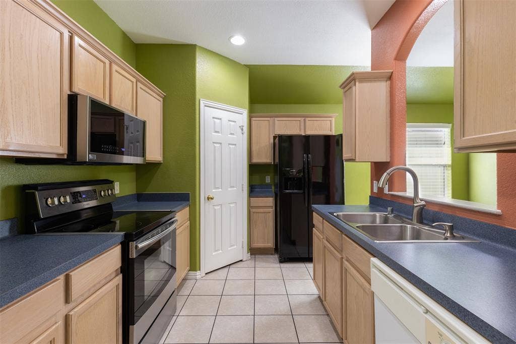 8614 Torreon Court, Dallas, TX 75217 Kitchen featuring sink, light tile floors, light brown cabinetry, and appliances with stainless steel finishes