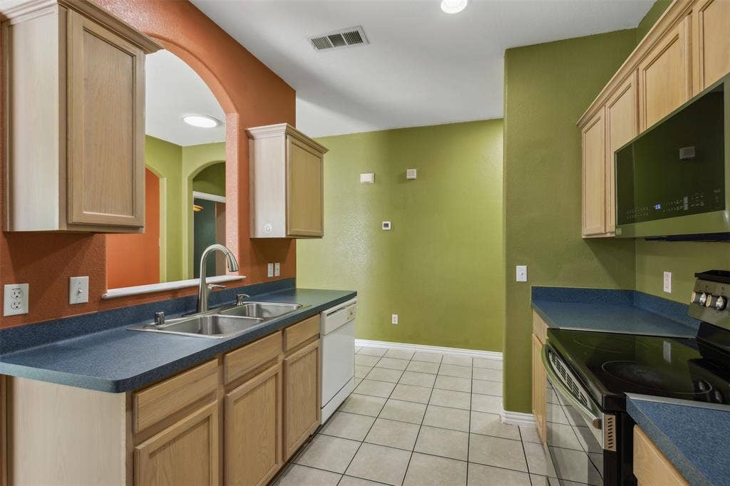 8614 Torreon Court, Dallas, TX 75217 Kitchen with light brown cabinets, sink, light tile floors, and appliances with stainless steel finishes