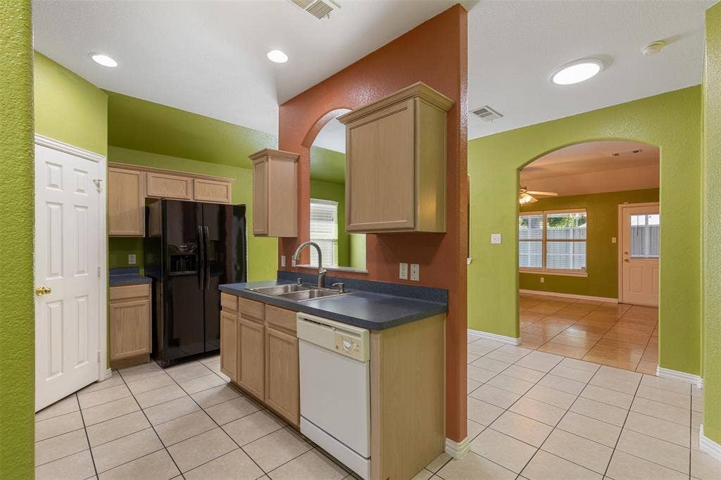 8614 Torreon Court, Dallas, TX 75217 Kitchen with ceiling fan, black fridge, white dishwasher, light tile floors, and sink