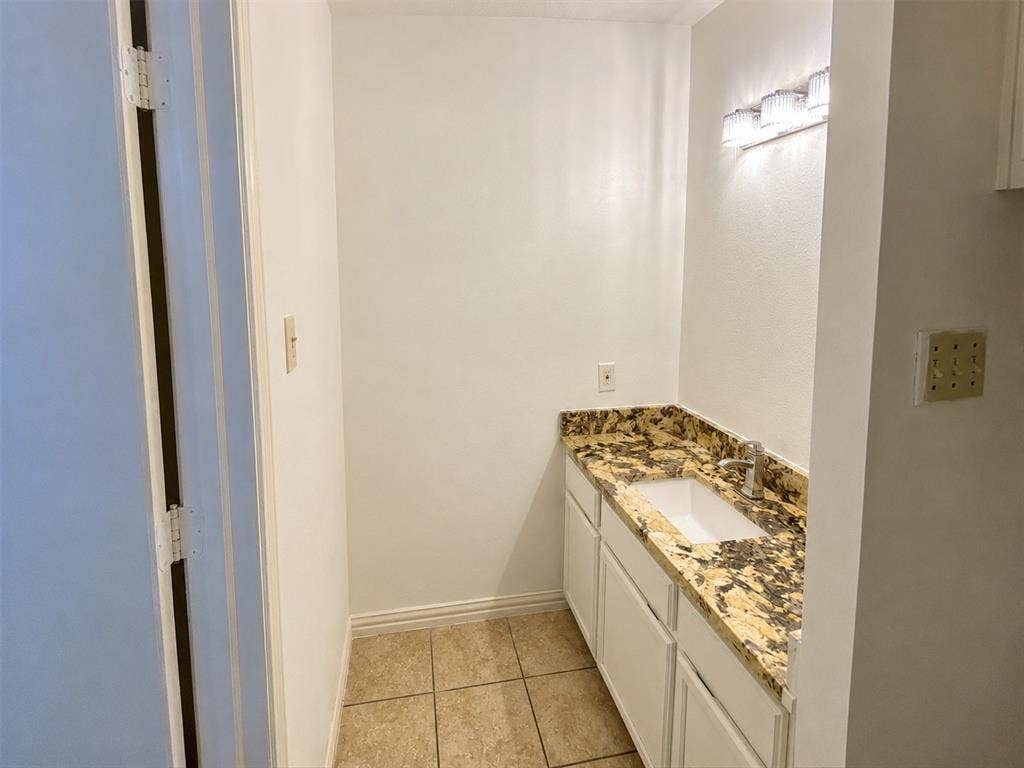 530 Rawls Circle, Irving, TX 75061 Vanity area featuring a gold and brown patterned countertop, undermount sink, and polished chrome faucet