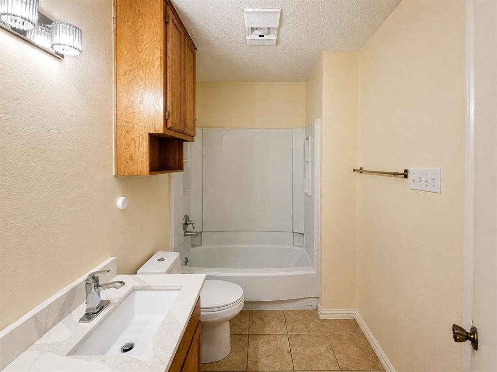 530 Rawls Circle, Irving, TX 75061 Bathroom featuring a white bathtub/shower combination, tile flooring, and a vanity with a white countertop and integrated sink