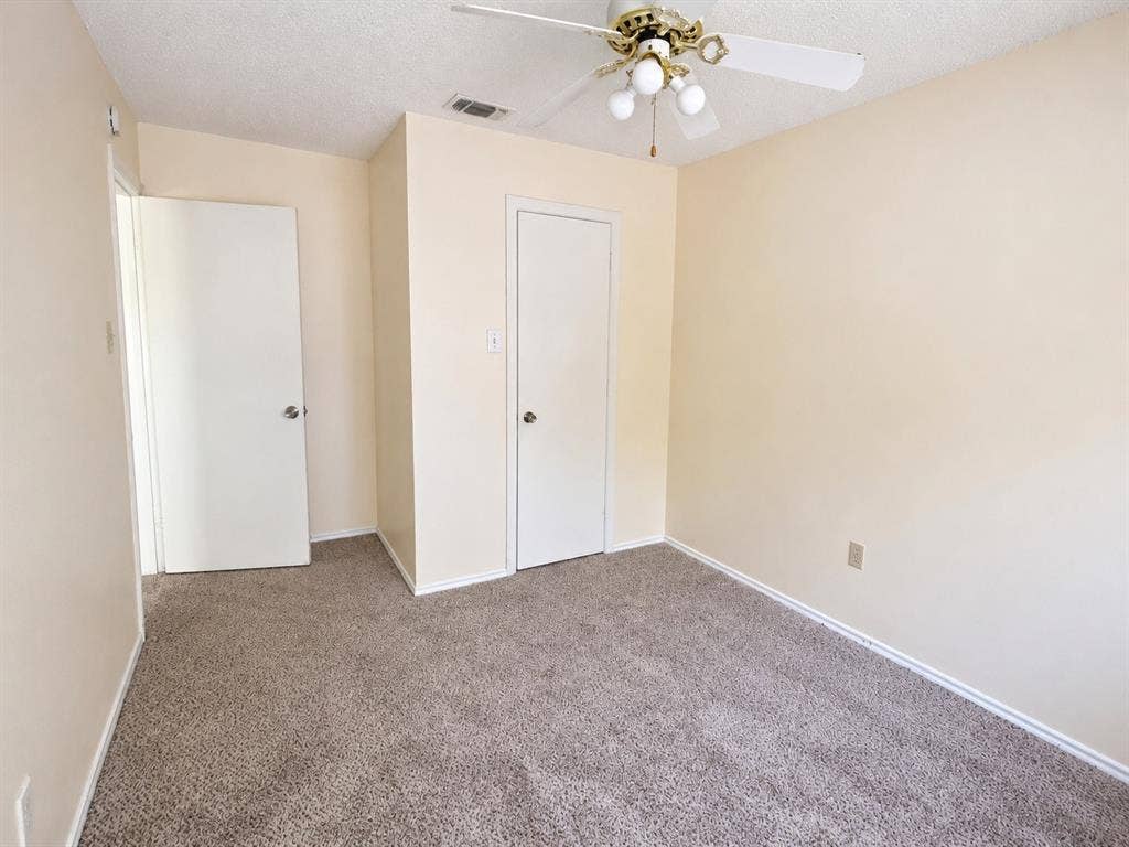 530 Rawls Circle, Irving, TX 75061 Carpeted room featuring a ceiling fan with light fixture, neutral-toned walls, and two white panel doors