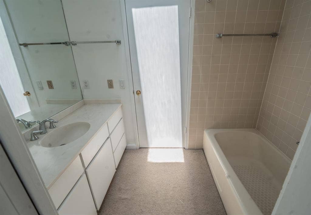 2818 Welborn Drive, #9, Dallas, TX 75219 Bathroom featuring a single vanity with an integrated sink, polished chrome faucet, and a large mirror