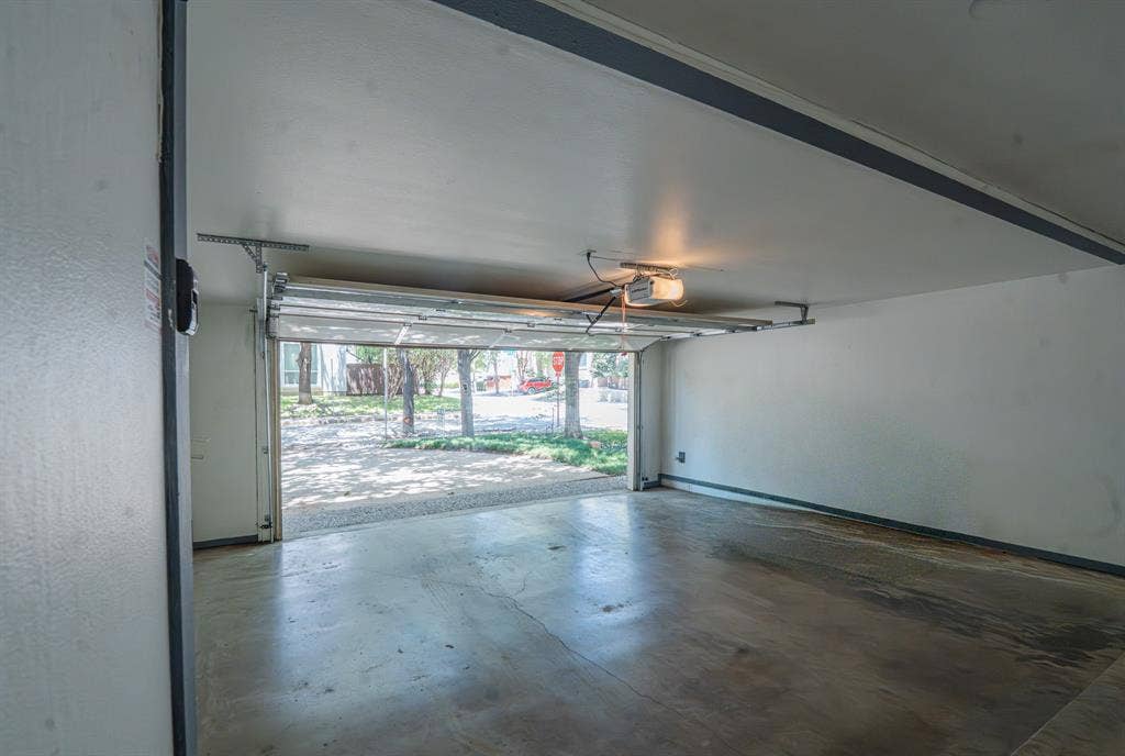 2818 Welborn Drive, #9, Dallas, TX 75219 Attached garage with a concrete floor, white painted walls, and an automatic garage door opener