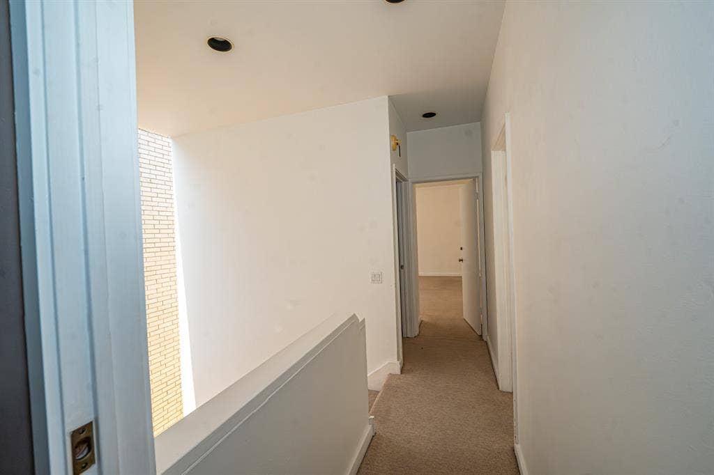 2818 Welborn Drive, #9, Dallas, TX 75219 Carpeted hallway with white walls, recessed lighting, and white trim turn right and go to one bedroom and turn left for second bedroom