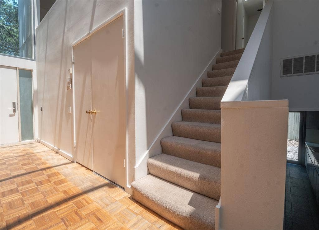 2818 Welborn Drive, #9, Dallas, TX 75219 Entryway featuring parquet wood-finish flooring, a carpeted staircase with a white railing, and white walls