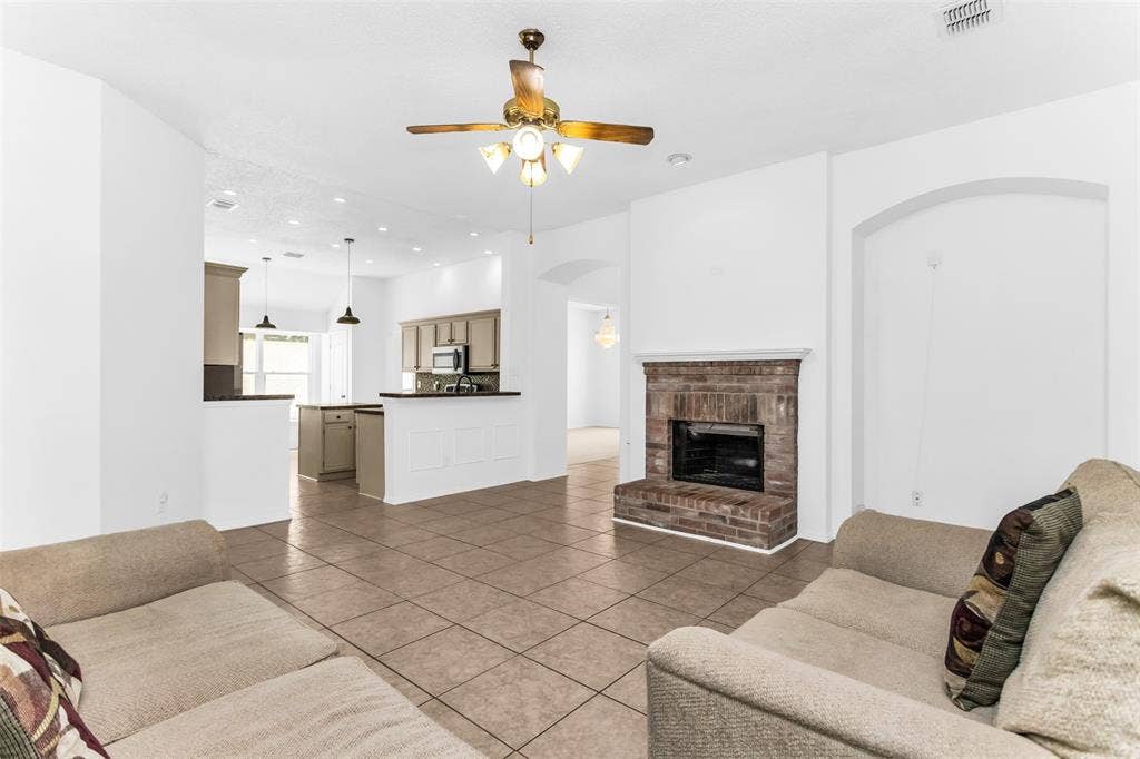 11404 Amber Valley Drive, Frisco, TX 75035 Open-concept living space featuring a brick-surround fireplace, tile flooring, and a ceiling fan with integrated lighting