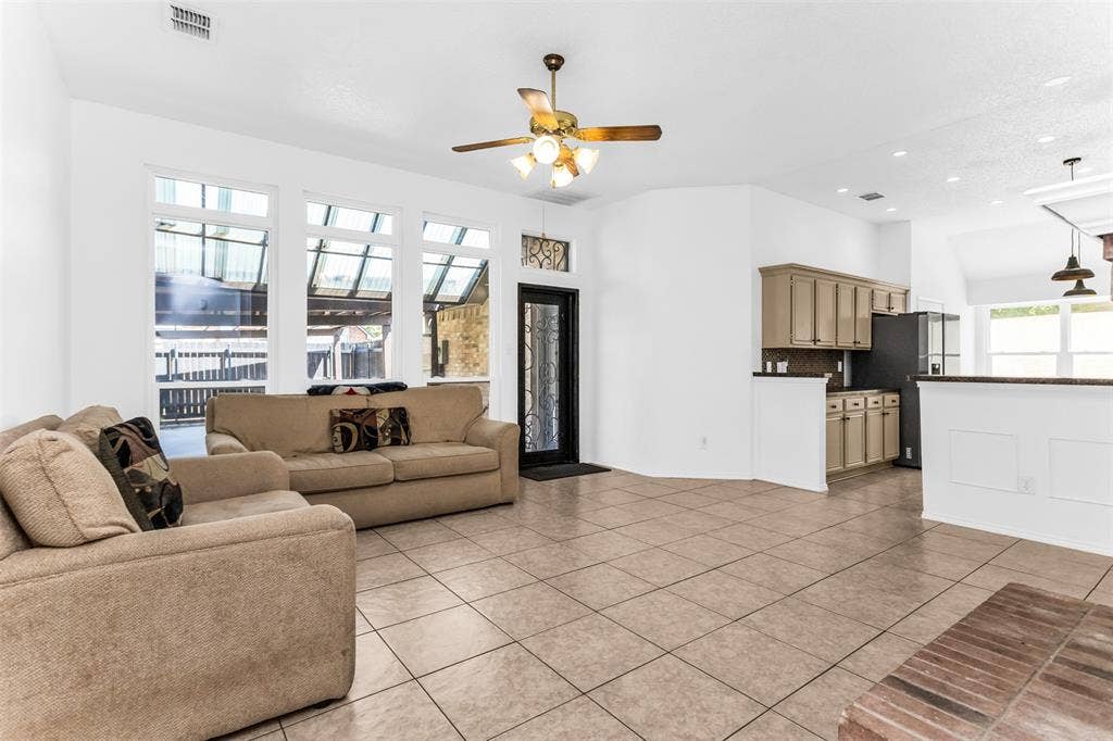 11404 Amber Valley Drive, Frisco, TX 75035 Open-concept living area featuring tile flooring, a ceiling fan with integrated lighting, and abundant natural light from multi-pane windows