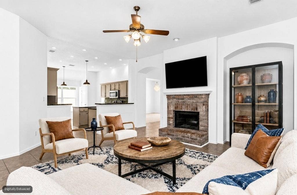 11404 Amber Valley Drive, Frisco, TX 75035 Brick-faced fireplace with a mantel, ceiling fan with integrated lighting, recessed lighting, arched entryway, and tile flooring
