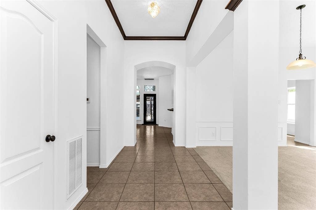 11404 Amber Valley Drive, Frisco, TX 75035 Foyer featuring tile flooring, archways, crown molding, and wainscoting