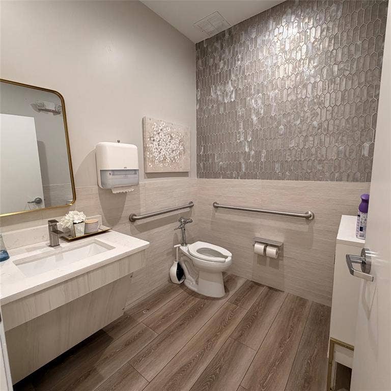 945 Stockton Drive, #7120, Allen, TX 75013 Bathroom featuring a modern vanity with integrated sink, gold-framed mirror, wood-finish flooring, and decorative accent wall tile