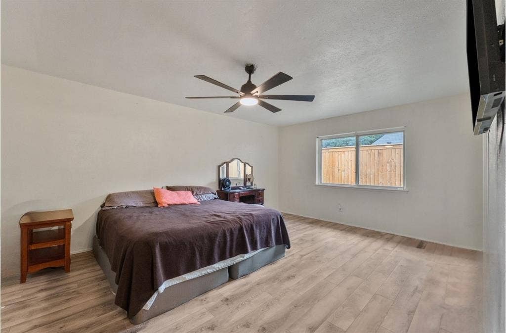 Recessed window with wood-framed glass, wood-finish flooring, and a ceiling fan with integrated lighting