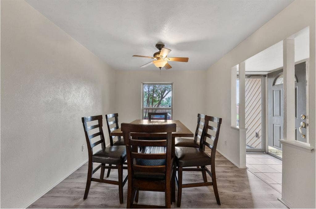 Wood-finish flooring throughout, ceiling fan with integrated lighting, and a window providing natural illumination