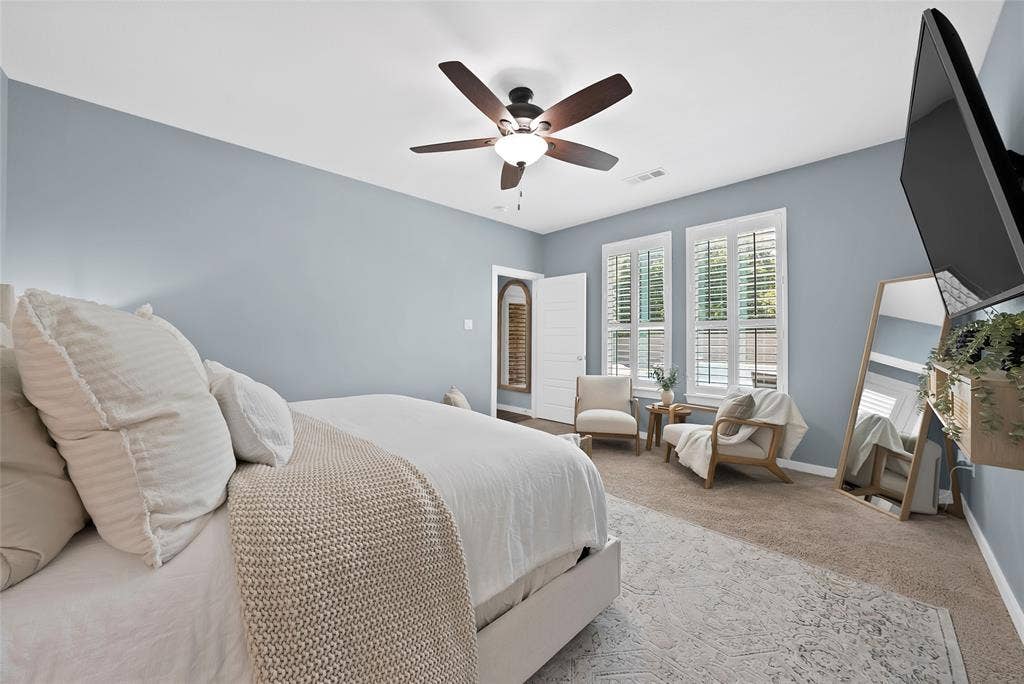Spacious bedroom featuring light blue walls and neutral carpet flooring