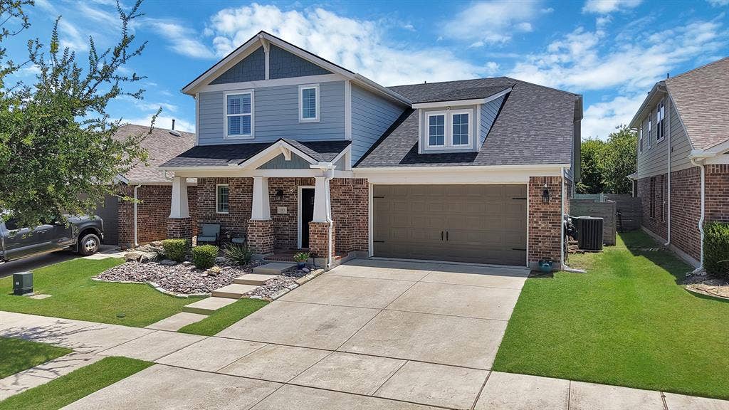 Two-story residence featuring brick and siding exterior, a two-car garage, and a covered front porch with columns