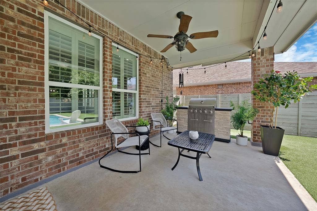 Covered patio featuring a ceiling fan, string lighting, and an outdoor kitchen with a built-in grill