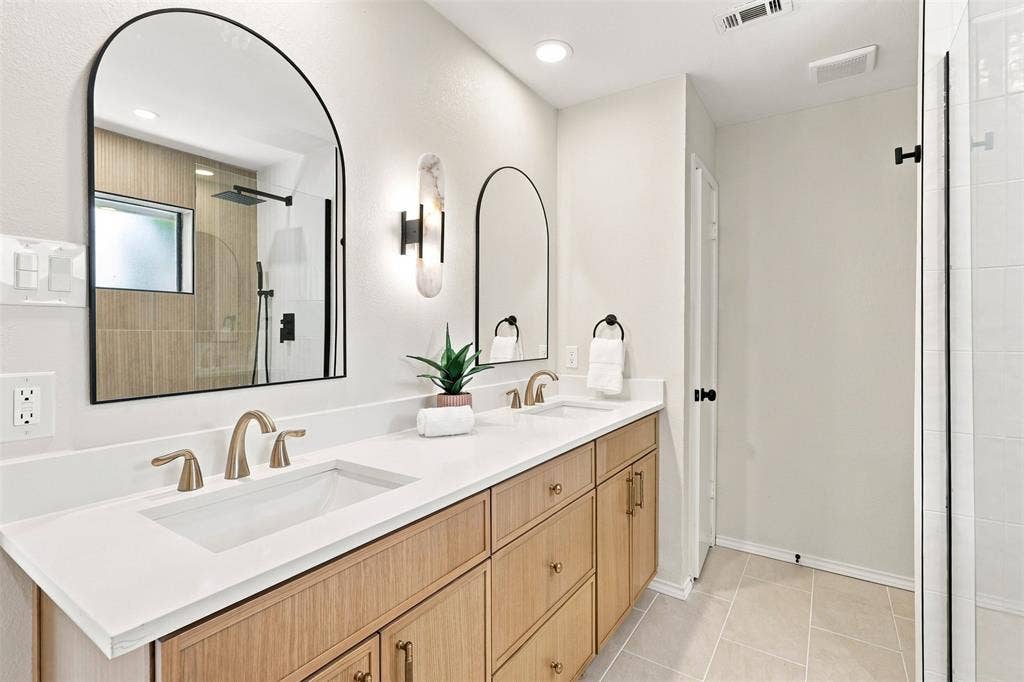 7321 Burke Circle, Plano, TX 75025 Dual arched mirrors, dual undermount sinks, wood-finish cabinetry, quartz countertops, and a glass-enclosed shower