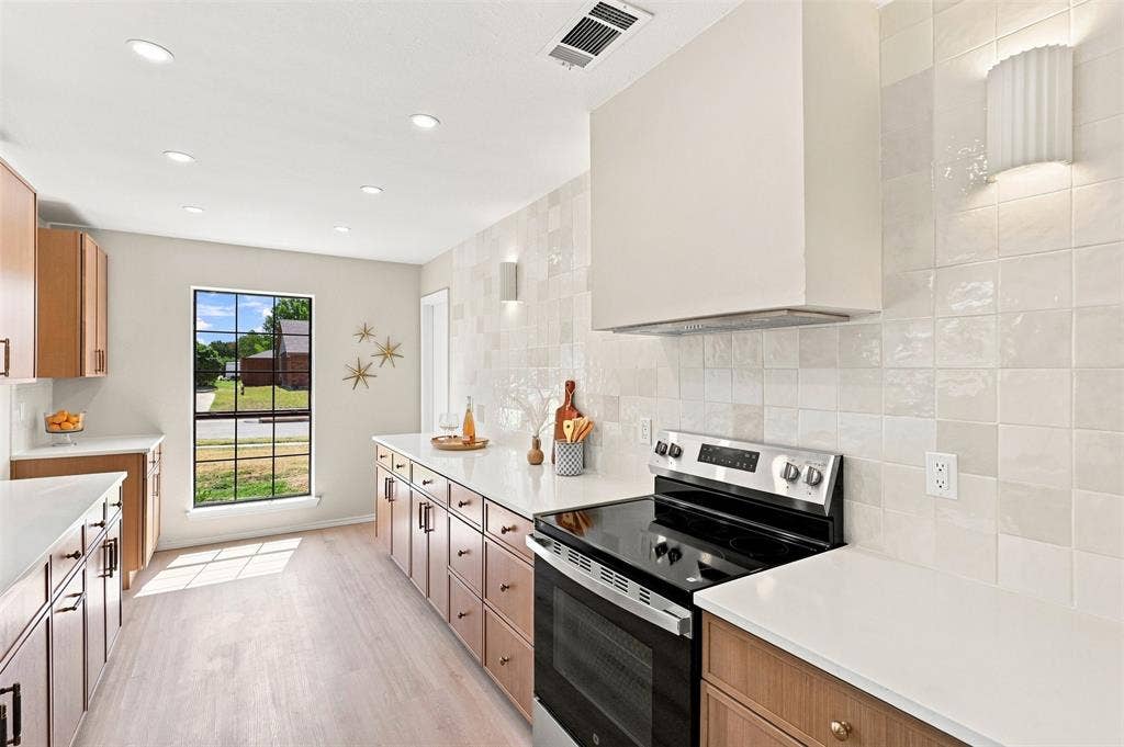 7321 Burke Circle, Plano, TX 75025 Recessed lighting, wood-finish cabinetry with black hardware, white countertops, tile backsplash, and a black range