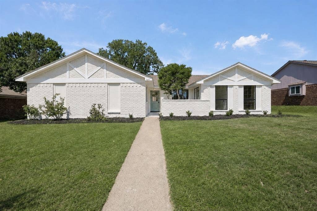 7321 Burke Circle, Plano, TX 75025 White brick facade with gabled roof lines, featuring black-framed windows, a concrete walkway, and landscaped front yard with shrubs