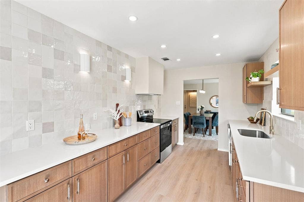 7321 Burke Circle, Plano, TX 75025 Modern kitchen featuring wood-finish cabinetry, light countertops, integrated stainless steel appliances, and recessed lighting