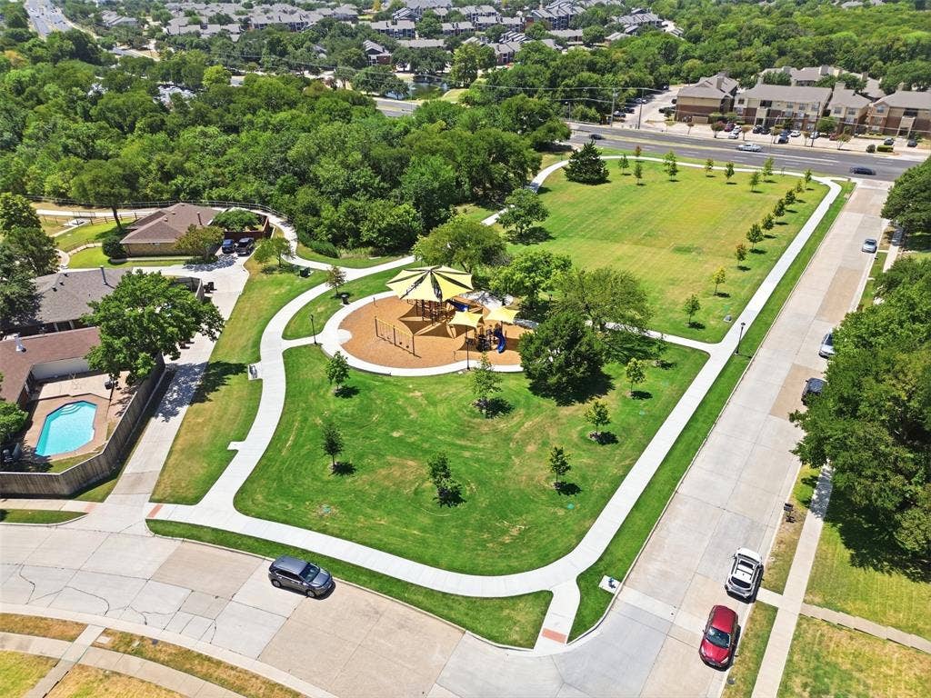 7321 Burke Circle, Plano, TX 75025 Expansive community park featuring a playground area, green space, and paved walking paths, surrounded by mature trees and residential properties