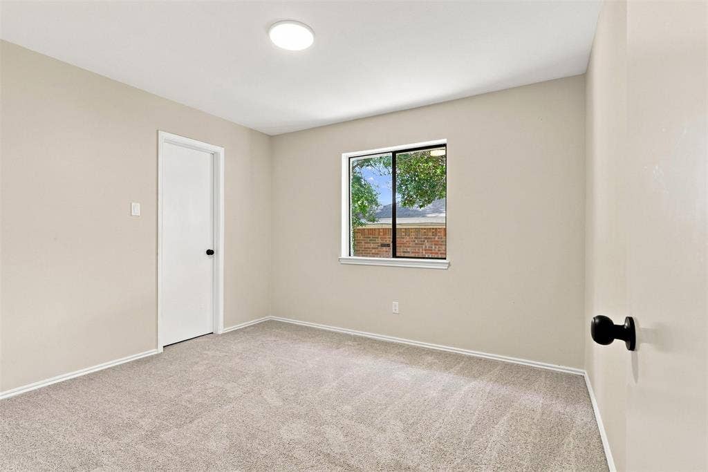 7321 Burke Circle, Plano, TX 75025 Neutral tone wall paint, light gray carpeting, white trim, recessed lighting, and a window with a brick exterior visible