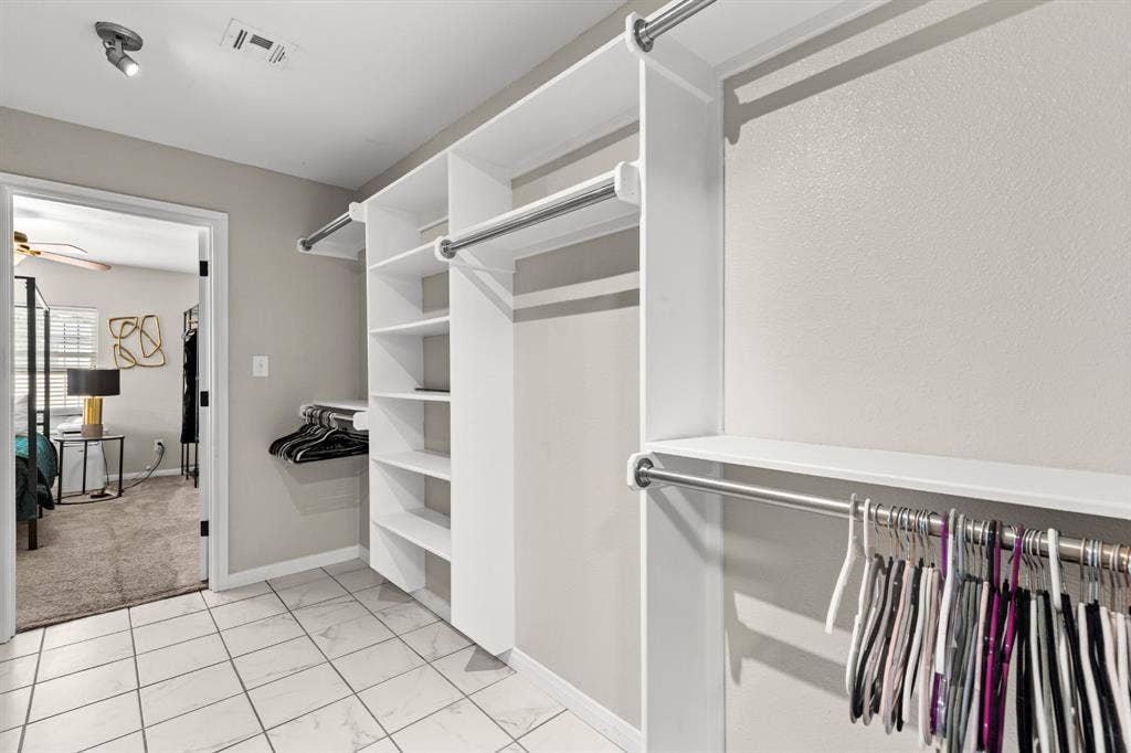 3700 Charlton Avenue, Waco, TX 76711 Walk-in closet featuring white built-in shelving, multiple hanging rods, and tile flooring