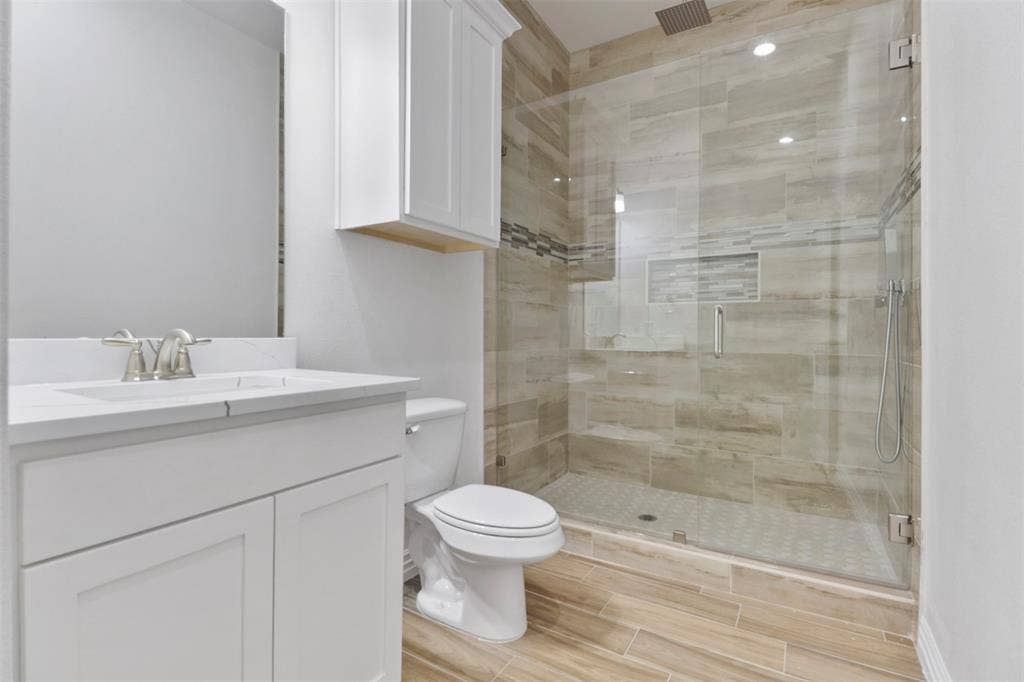 4112 Balch Drive, Dallas, TX 75216 Bathroom featuring a glass-enclosed shower with tile surround, a built-in shower niche, and a rain shower head