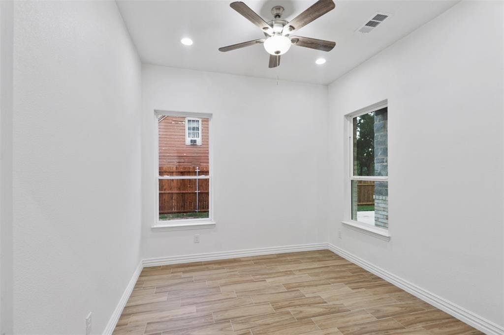 4112 Balch Drive, Dallas, TX 75216 Bright, airy bedroom featuring gleaming wood-finish flooring, fresh white walls, and abundant natural light from two large windows